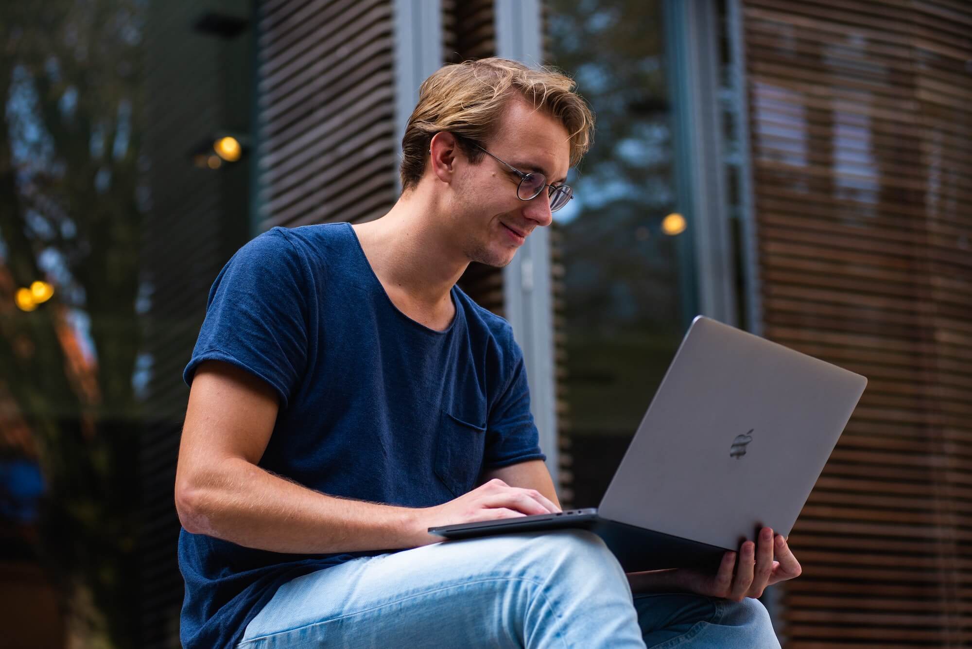 Young man smiling as he uses a laptop