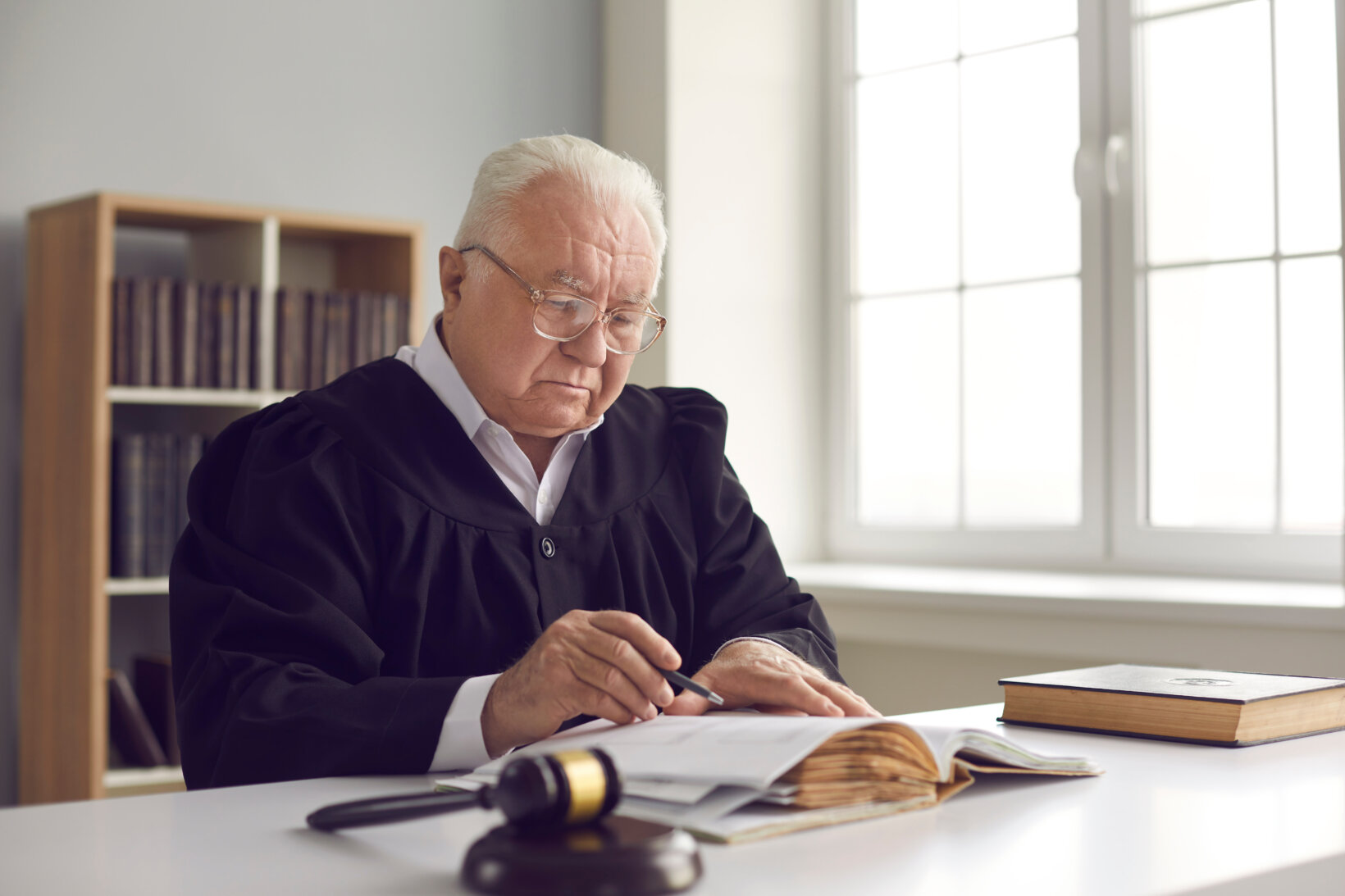 A male judge reading a document in his chambers.
