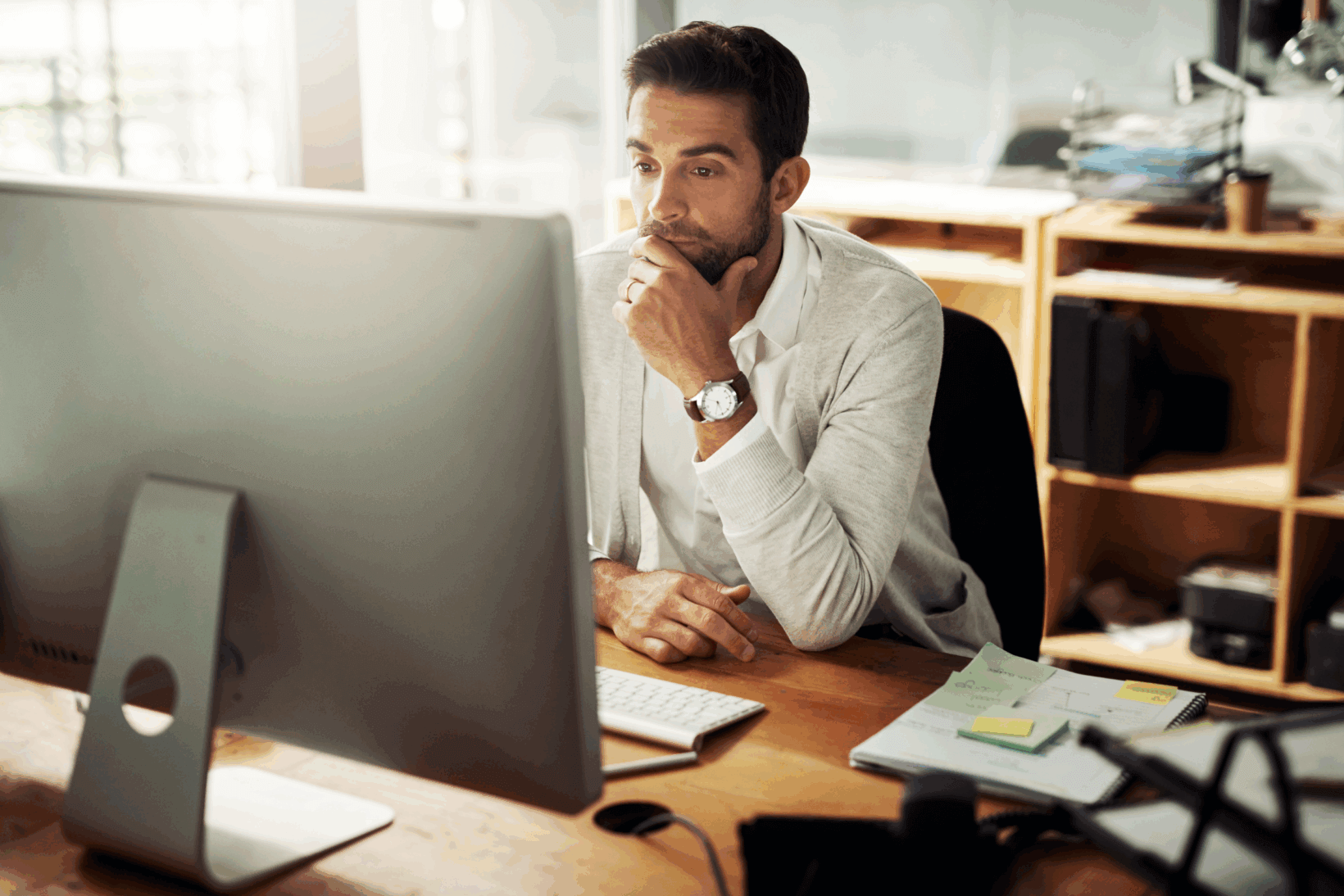A male attorney looking at his desktop monitor with a look of confusion and uncertainty due to a recent cybersecurity attack