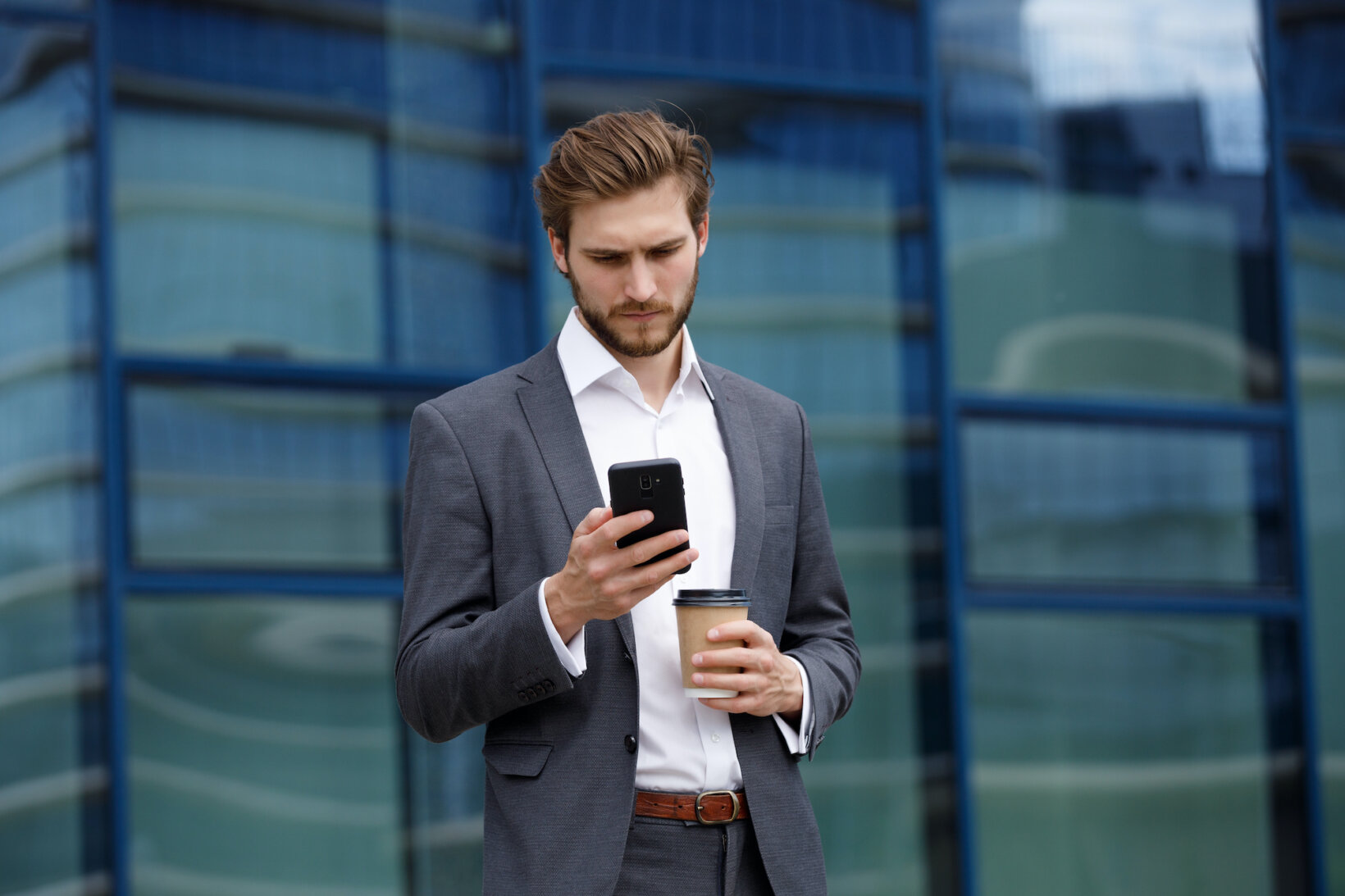 Young attorney checking a Fastcase alert on his phone while holding a coffee