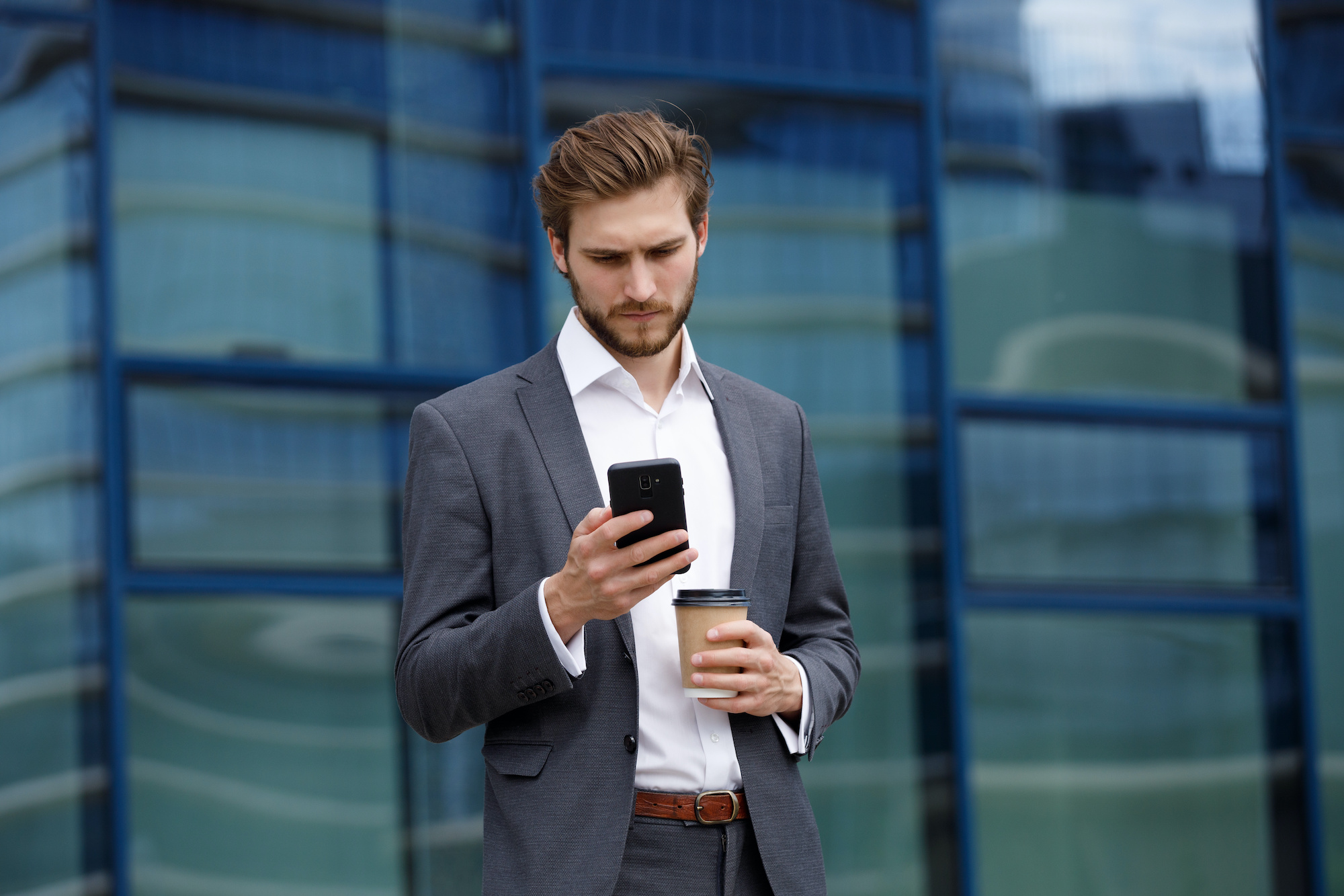 Young attorney checking a Fastcase alert on his phone while holding a coffee