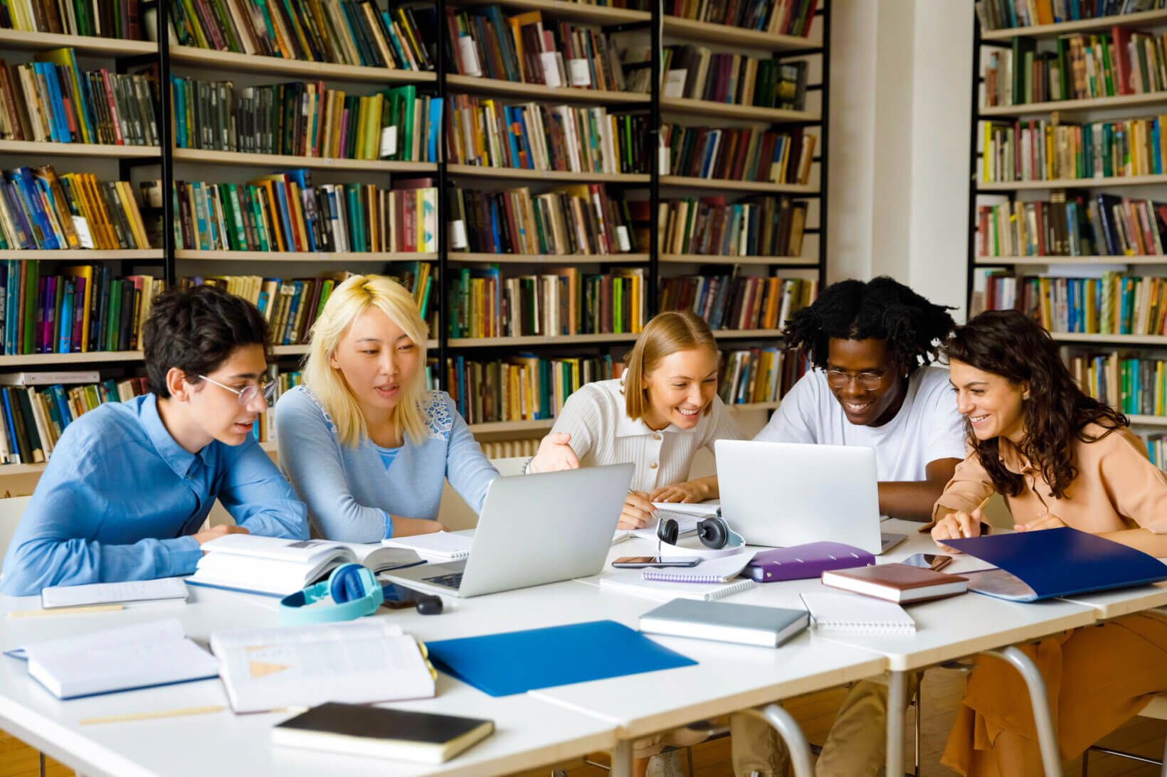 A group of Texas law school students in a library working on homework on their laptops