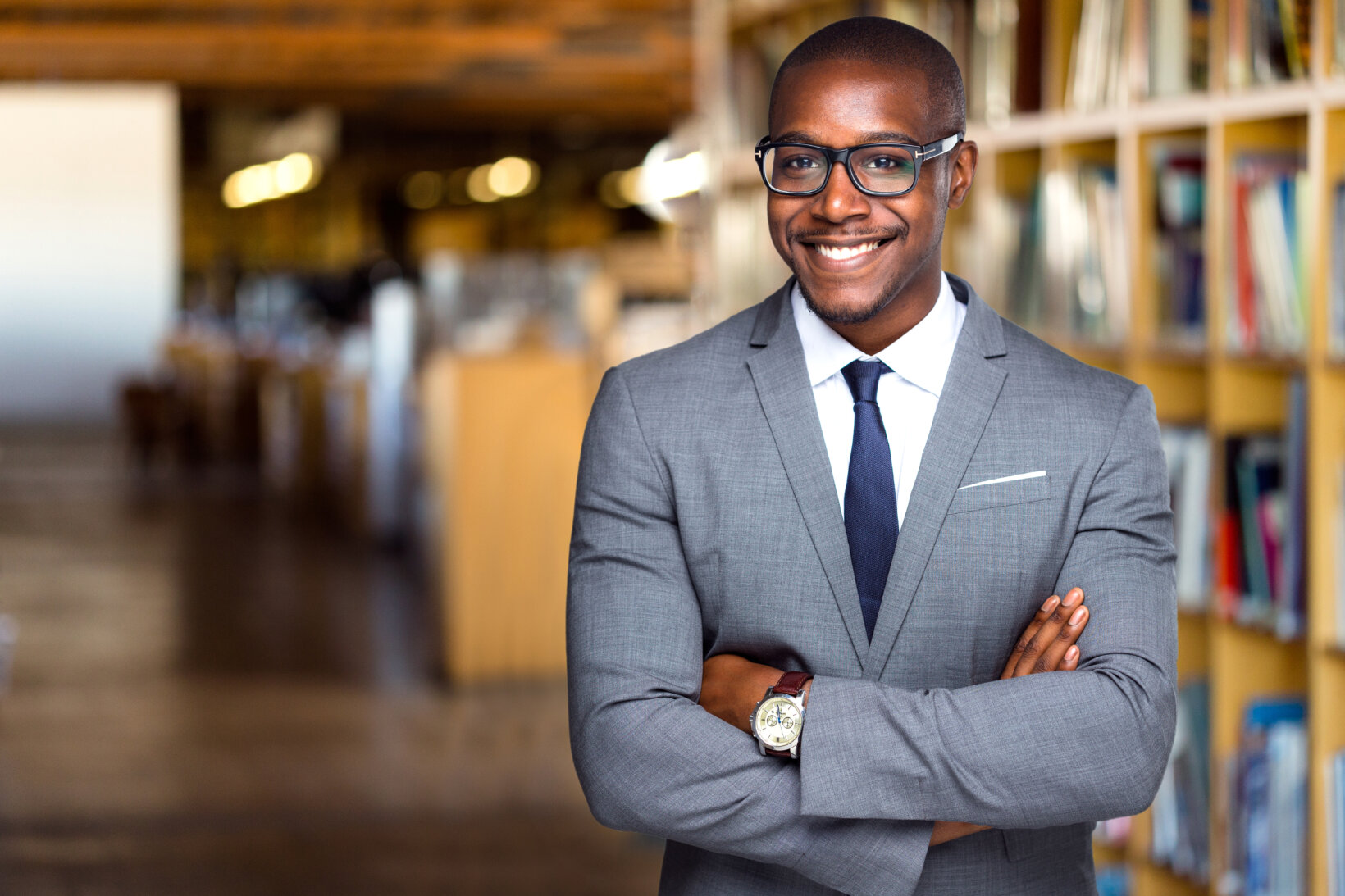 Smiling and cheerful attorney standing in front of a bookshelf in a law library