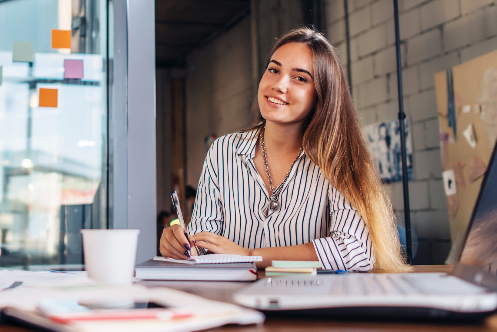 Smiling female law school student writing looking at camera sitting at table