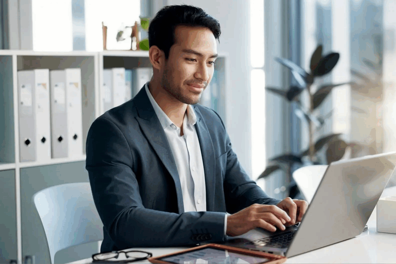 A young happy male attorney sitting at his desk typing on a laptop